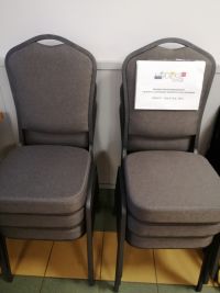 Krzesła tapicerowane z metalową ramą ułożone w dwóch słupkach z informacją o dofinansowaniu projektu