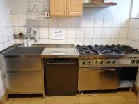 wymieniona zabudowa kuchenna ze stali nierdzewnej, od lewej zlew, blat roboczy, pod nim zmywarka, kuchnia gazowa