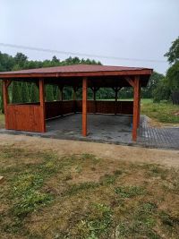 altana stojąca na kostce brukowej, przed nią murawa, w tle drzewa i niebo