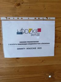 ściana wewnętrzna altany z desek z umieszczoną informacją o dofinansowaniu projektu